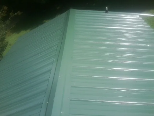 New green metal panels meeting at the ridge of a roof — Flat Roof Repair work by our crew in North Hollywood