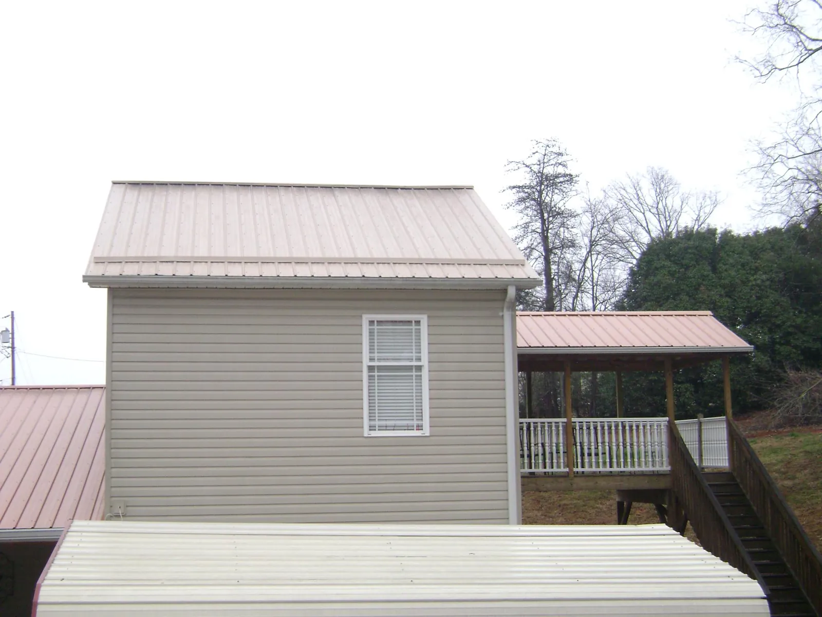Tan metal roofs on a two story addition and attached porch, from a Roof Replacement job in North Hollywood