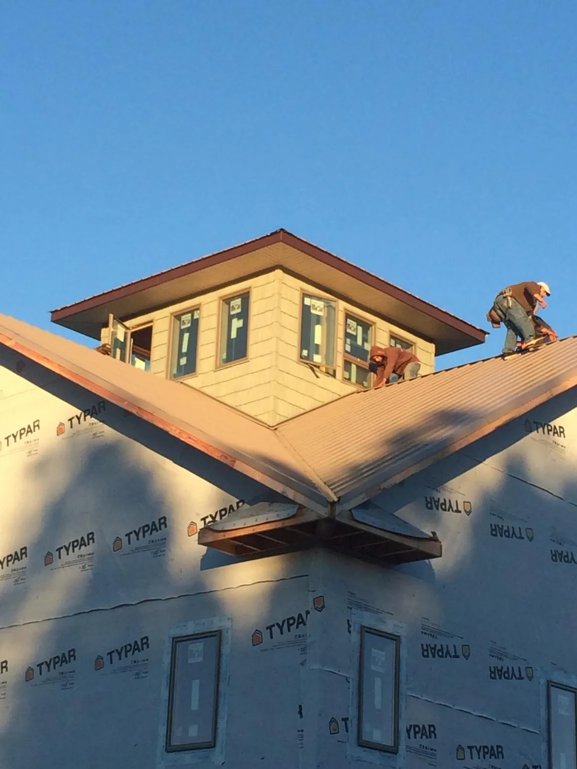 Roofers working around a rooftop cupola on a new metal roof at sunset — Roof Waterproofing in North Hollywood by Roofing Brothers